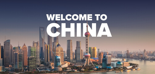 Promotional banner with the text 'WELCOME TO CHINA' overlaid on an image of the Shanghai skyline during the day. The cityscape includes recognizable landmarks such as the Oriental Pearl Tower and the Shanghai World Financial Center, set against a backdrop of clear skies with the Huangpu River in the foreground.